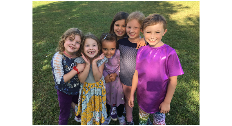 six smiling children in the grass